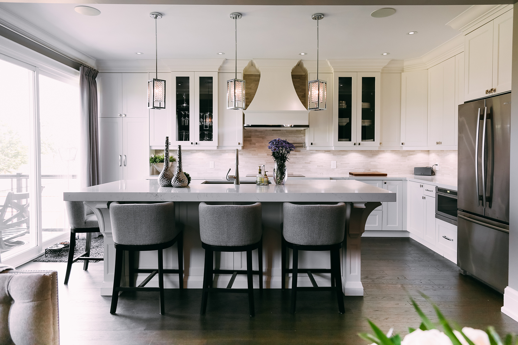 Modern walnut kitchen with a waterfall Calacatta island and brass globe pendants